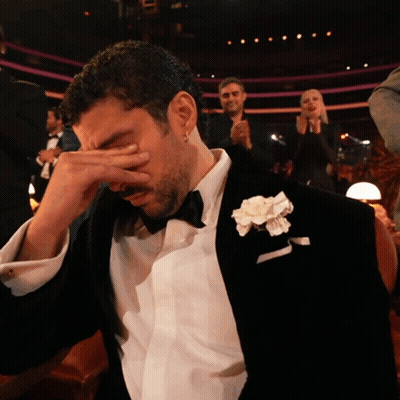 Man In Tuxedo With White Flower Covering Face GIF