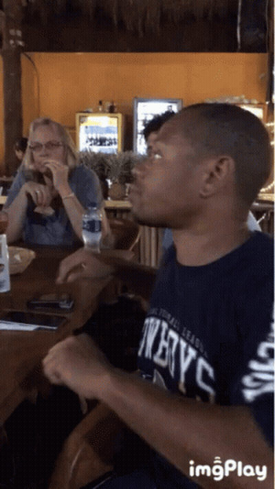 Man In Twelve C Shirt Sitting At Table GIF