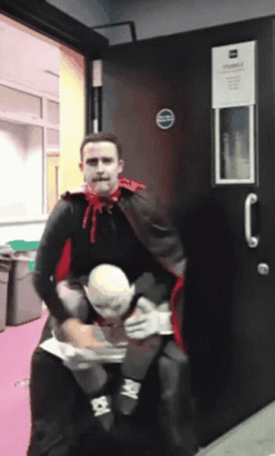 Man In Vampire Costume Carrying Man In White Mask GIF