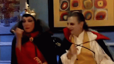 Man In Vampire Costume Next To Woman In Crown GIF