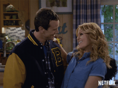 Man In Varsity Jacket With B Hugging Woman GIF