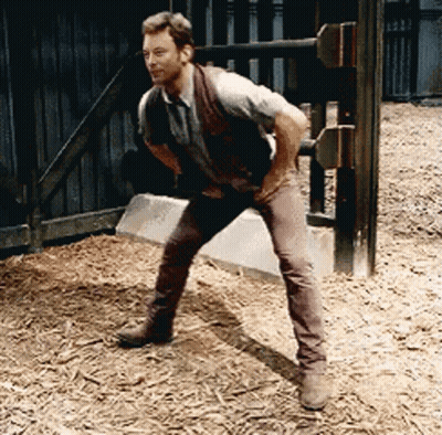 Man In Vest And Brown Pants Standing On One Leg GIF