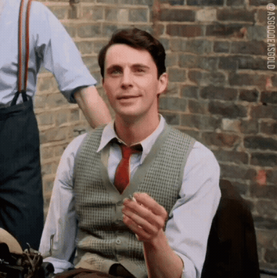 Man In Vest And Tie Smoking By Brick Wall GIF
