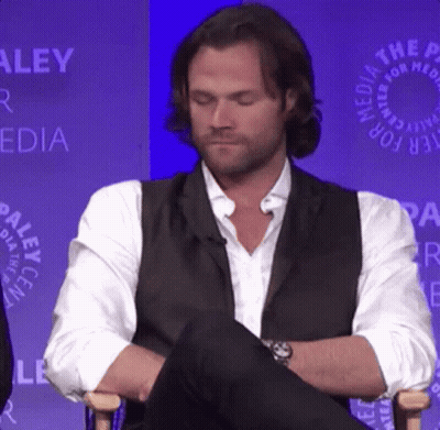 Man In Vest And White Shirt Sitting With Legs Crossed GIF