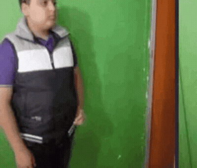 Man In Vest Holding Knife At Green Wall GIF