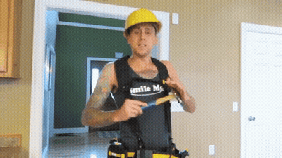 Man in Vest Saying Smile Me Holding Hammer