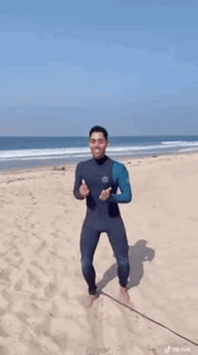 Man In Wetsuit Dancing On Beach GIF