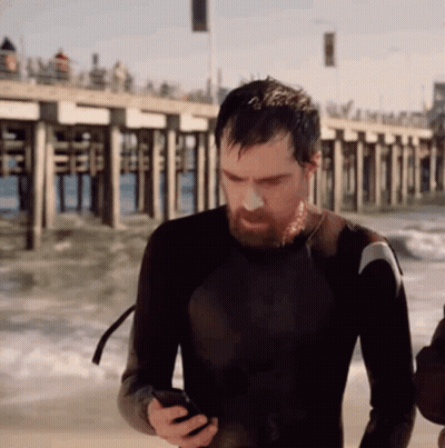 Man In Wetsuit Looking At Cell Phone GIF