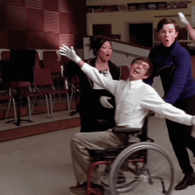 Man In Wheelchair Arms Outstretched Surrounded By People GIF