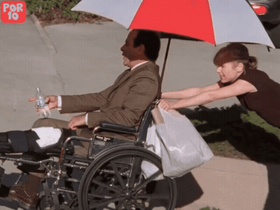 Man In Wheelchair Pushed By Woman Under Umbrella GIF