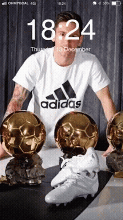 Man In White Adidas Shirt Surrounded By Soccer Balls And Cleats GIF