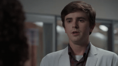 Man In White Coat Looks At Woman In Plaid Shirt GIF