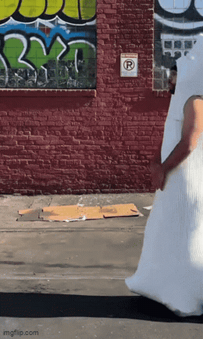 Man In White Costume Walking Past Graffiti Wall GIF