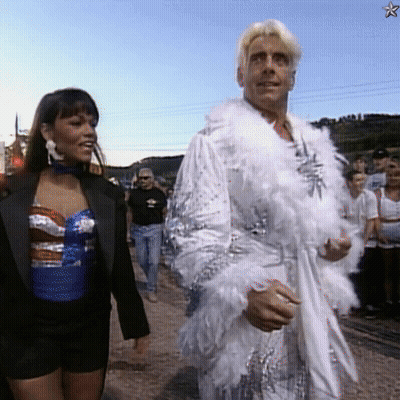 Man In White Feathered Robe Walking With Woman GIF