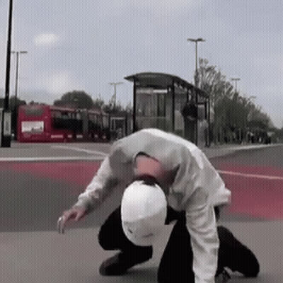 Man In White Helmet Kneeling On Street GIF