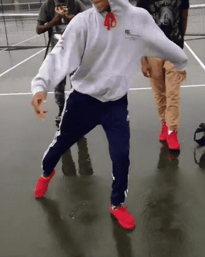 Man In White Hoodie And Blue Pants Dancing On Tennis Court GIF