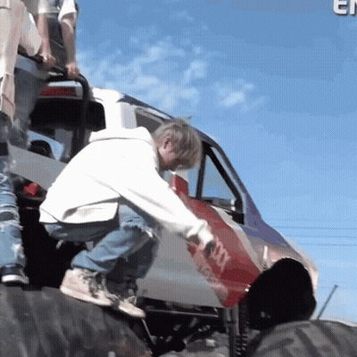 Man In White Hoodie Kneeling On Tire Next To Jeep GIF