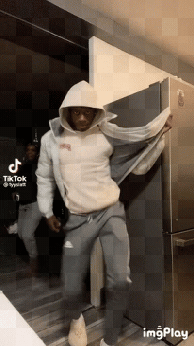 Man In White Hoodie Standing By Refrigerator GIF