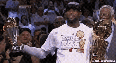 Man In White Hot Shirt Holding Two Trophies GIF