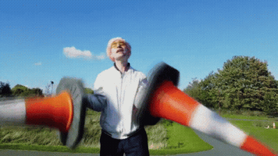 Man In White Jacket Holding Two Traffic Cones GIF