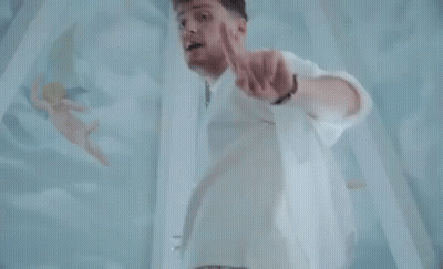 Man In White Pointing At Camera With Angels GIF
