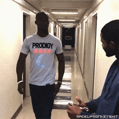 Man In White Prodigy T-Shirt Walking Down Hallway GIF