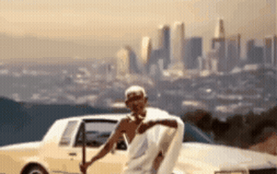 Man In White Robe By Car With City Background GIF