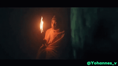Man In White Robe Holding Torch In Dark GIF