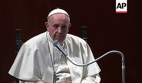Man In White Robe Sitting At Microphone GIF