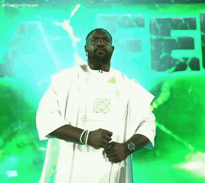 Man In White Robe Standing In Front Of Green Sign Saying EE GIF