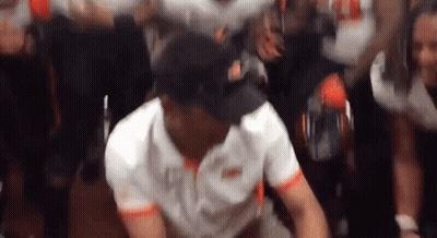 Man in White Shirt and Black Hat Dancing in Front of Crowd