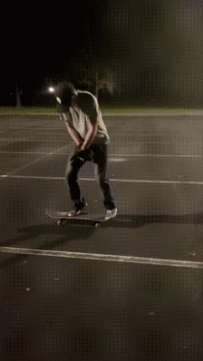 Hombre con camisa blanca y sombrero negro en patineta de noche GIF