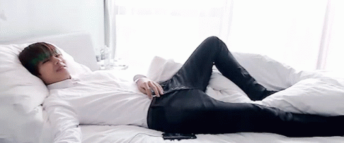 Man In White Shirt And Black Jeans Lying On Bed GIF