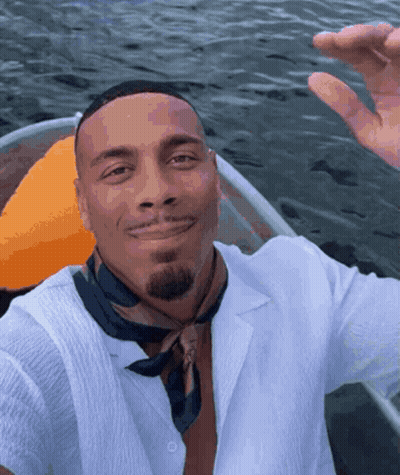 Man In White Shirt And Black Scarf Smiling In Boat GIF