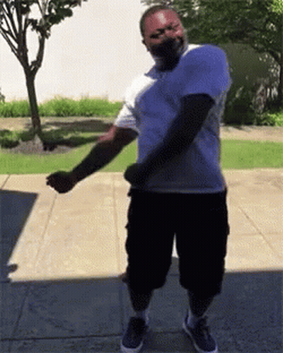 Man In White Shirt And Black Shorts Dancing On Sidewalk GIF