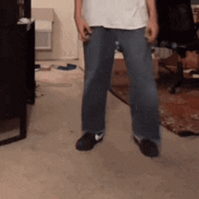 Man In White Shirt And Blue Jeans Standing On Carpet GIF