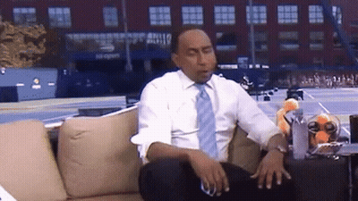 Man in White Shirt and Blue Tie on Couch in Front of US Open Sign