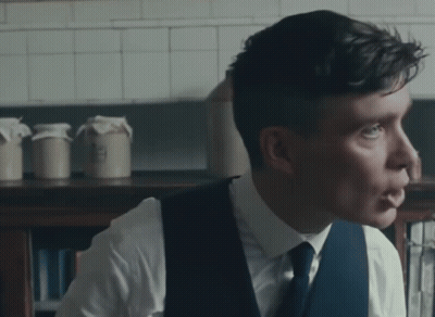 Man In White Shirt And Blue Vest Looking To Side GIF