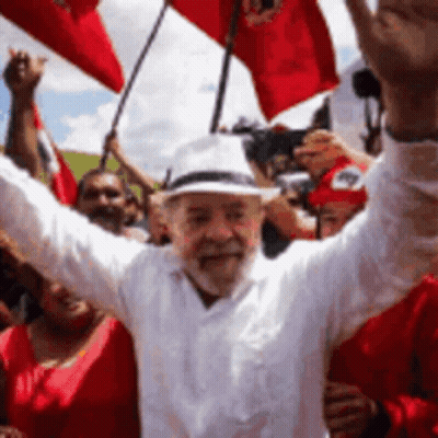 Man In White Shirt And Hat Holding Red Flags GIF