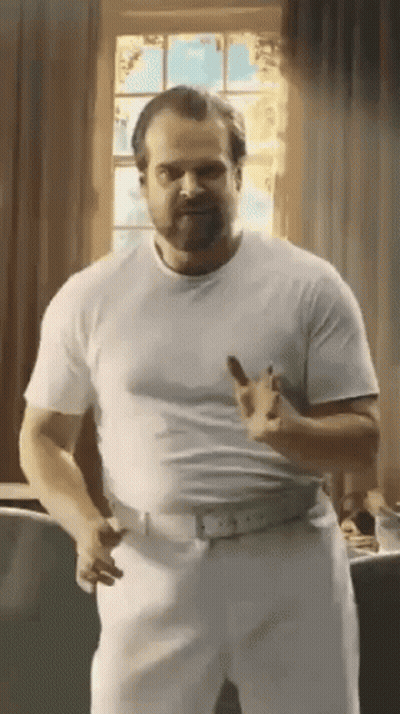 Man In White Shirt And Pants Standing By Window GIF