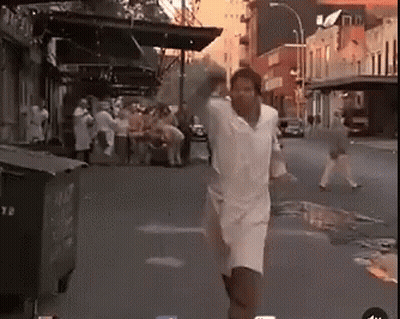 Man In White Shirt And Shorts Running Down Street GIF