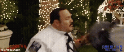 Man in White Shirt and Tie in Front of Paul Blart 2 Mall Cop Sign