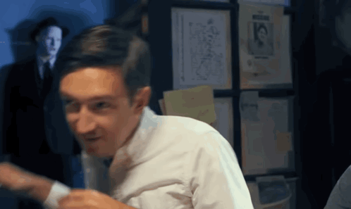 Man In White Shirt And Tie In Front Of Wall With Papers 15 GIF