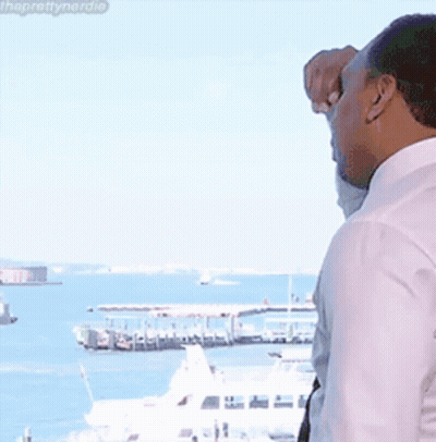 Man In White Shirt And Tie Looking Out Window At Ocean GIF