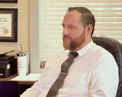Man In White Shirt And Tie Sitting In Front Of Dad Sign GIF