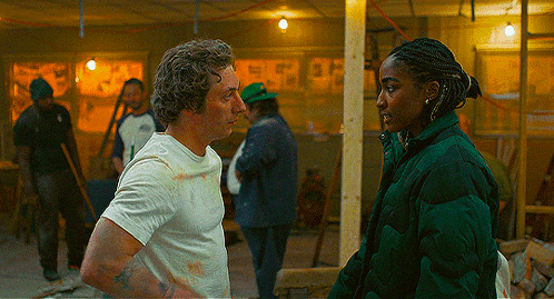 Man In White Shirt And Woman In Green Jacket Talking GIF