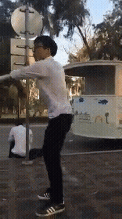 Man In White Shirt Doing Trick On Street GIF