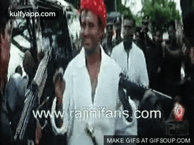 Man In White Shirt Holding Gun In Front Of Crowd GIF