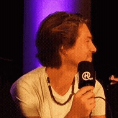 Man In White Shirt Holding Microphone With Letter R GIF