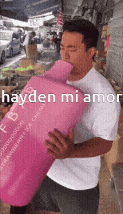 Man In White Shirt Holding Pink Container Saying Hayden Mi Amor GIF